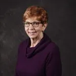 Smiling, older, female patient wearing a purple shirt.