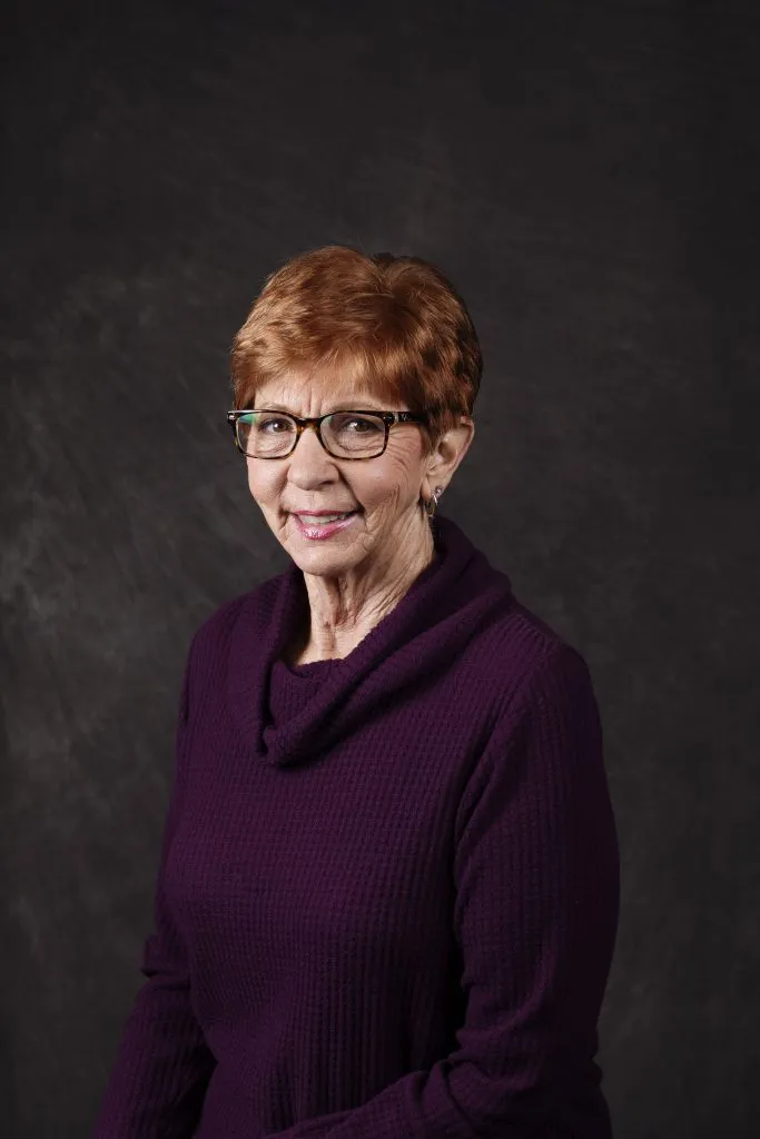 Smiling, older, female patient wearing a purple shirt.