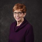 Smiling, older, female patient wearing a purple shirt.
