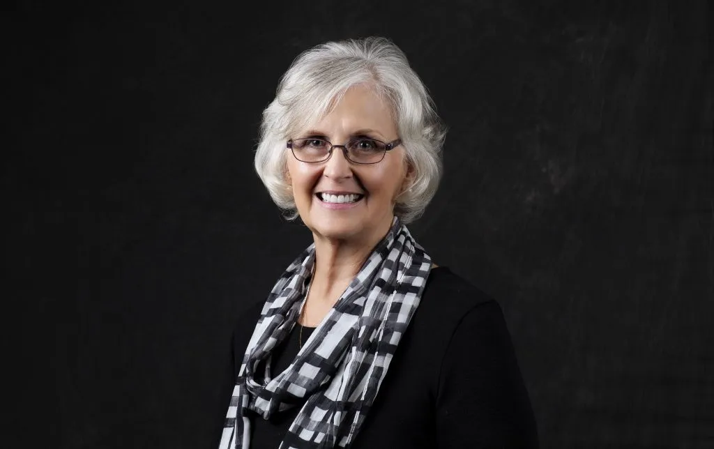 Smiling, older, female patient wearing black with a plaid scarf