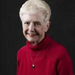 Smiling, older, female patient wearing a red turtle neck sweater