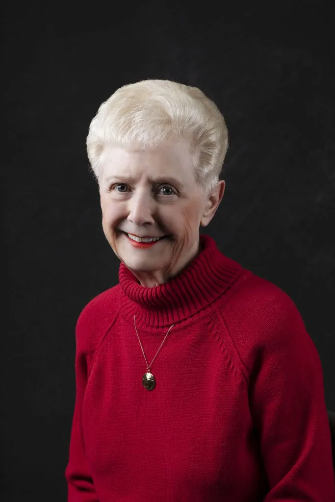 Smiling, older, female patient wearing a red turtle neck sweater