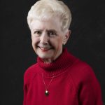 Smiling, older, female patient wearing a red turtle neck sweater