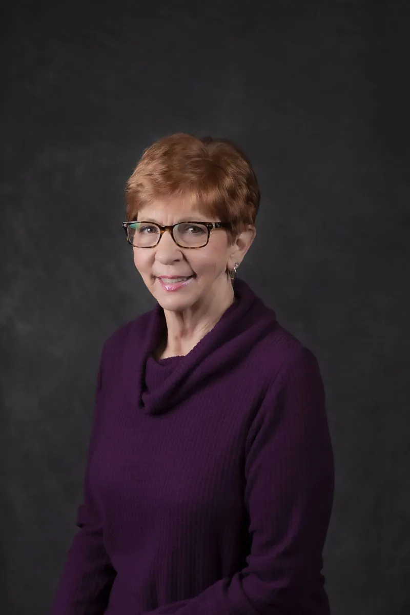 Smiling, older, female patient wearing a purple shirt.